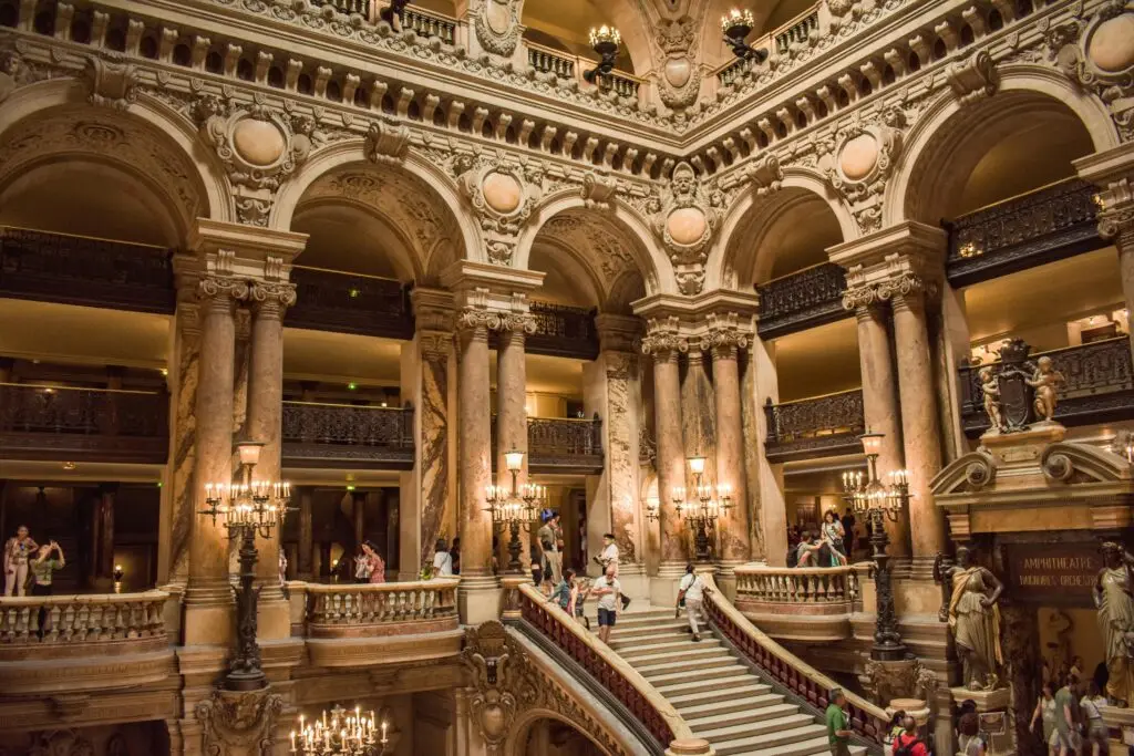 Majestic interior view of Palais Garnier with ornate staircase and sculptures in Paris.