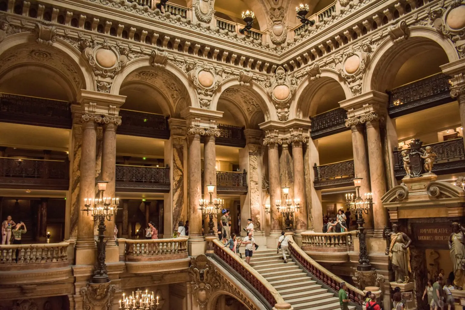 Majestic interior view of Palais Garnier with ornate staircase and sculptures in Paris.