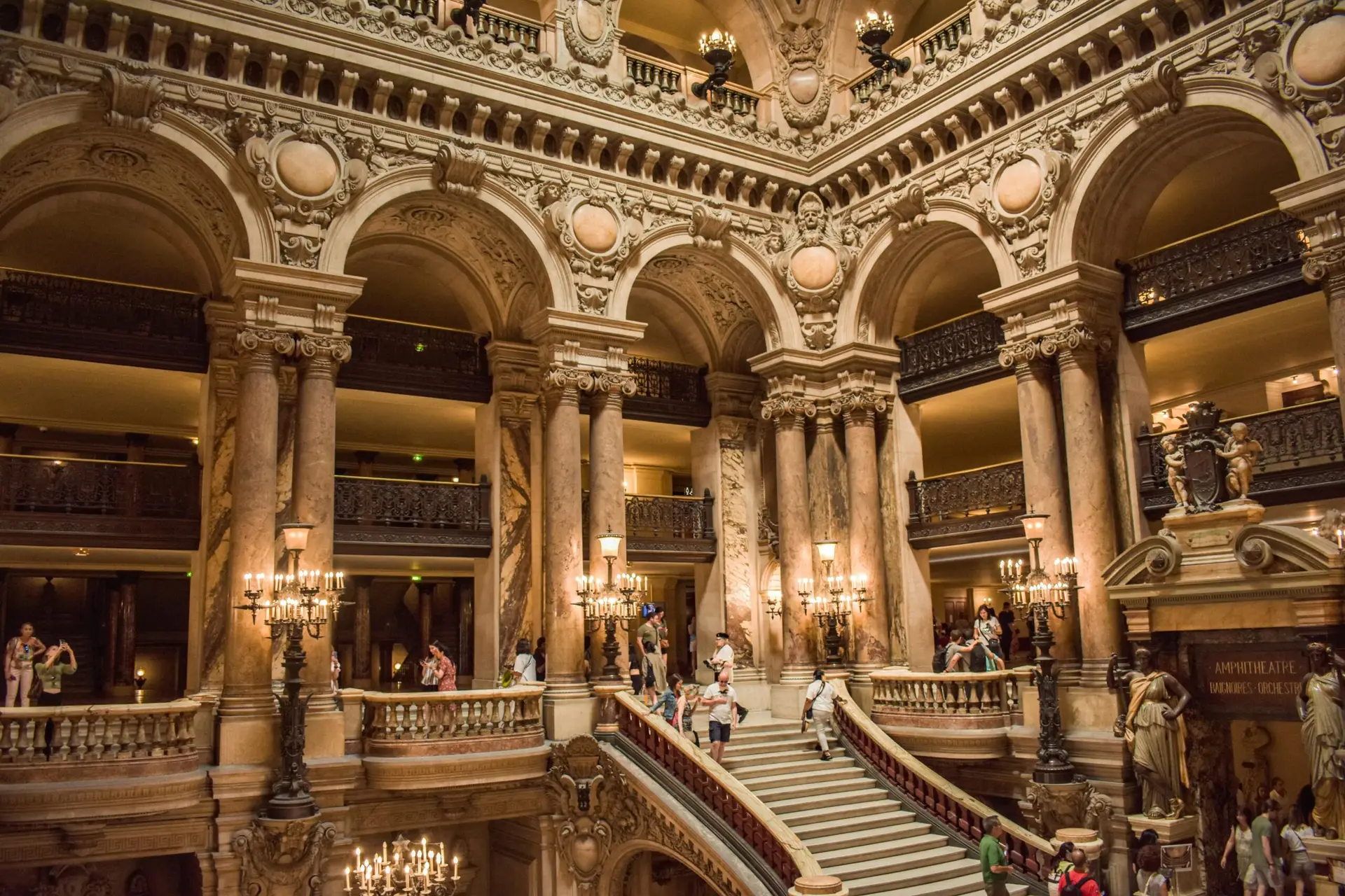 Majestic interior view of Palais Garnier with ornate staircase and sculptures in Paris.