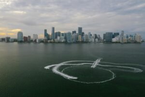 Aerial shot of Miami's skyline with watercraft patterns on the ocean surface.