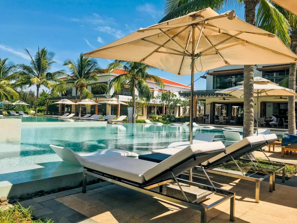 Experience relaxation at a luxury resort poolside, featuring palm trees and loungers for a perfect summer vacation.