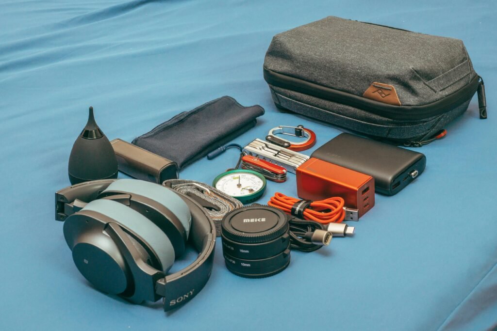 Flat lay of travel gear including headphones, a compass, power bank, and accessories.